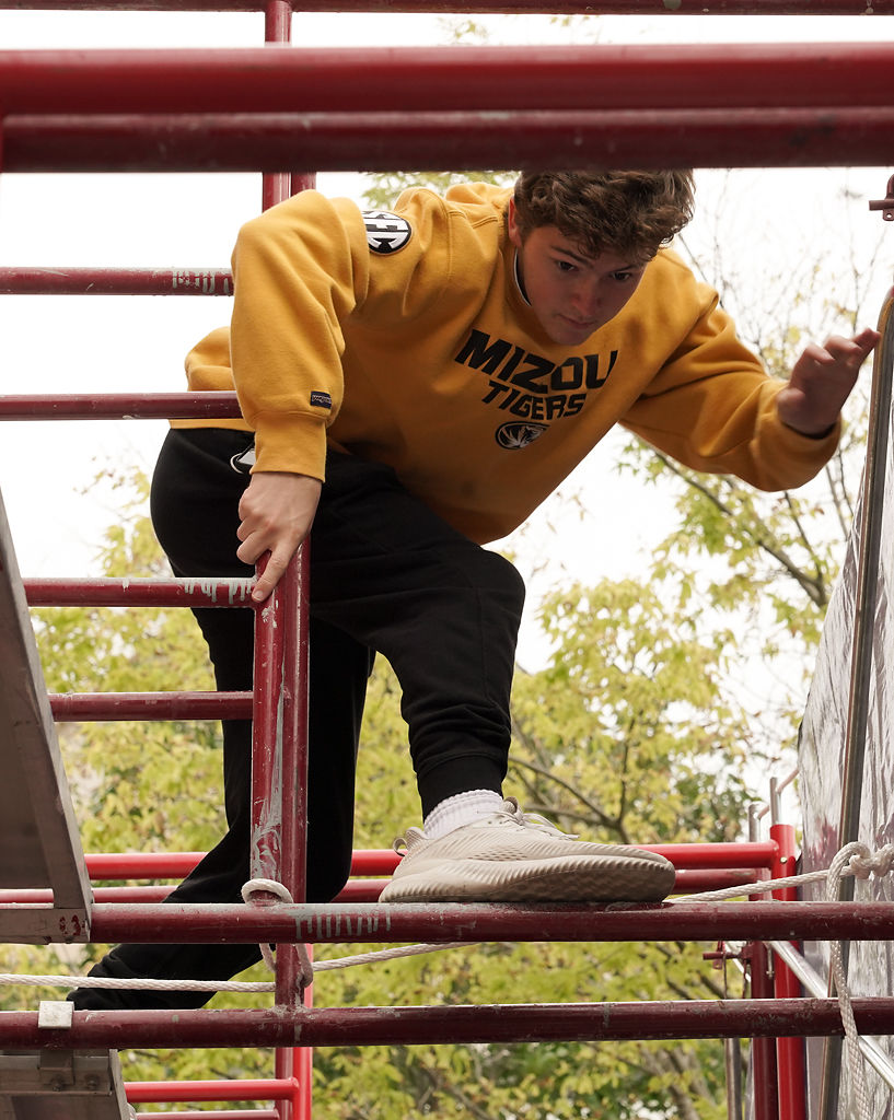 Grant Wall climbs through scaffolding for homecoming house decorations